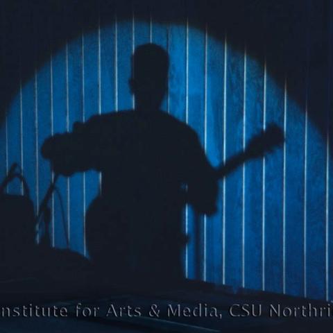 Spotlight shadow of a man with a guitar