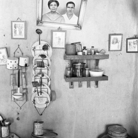 A picture and crockery set hanging off the wall and vessels places on the table.