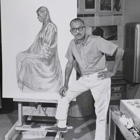 A man posing in front of a large portrait sketch.