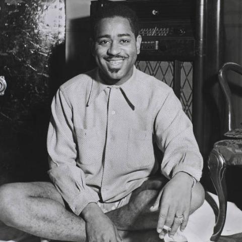 A man smiling for a picture sitting on the floor.