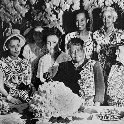 Woman surrounded by friends, including Lena Horne, behind a birthday cake