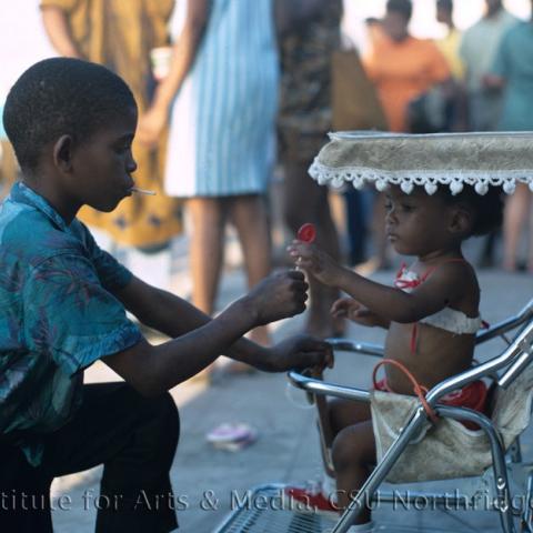 Child handing a lollypop to a baby