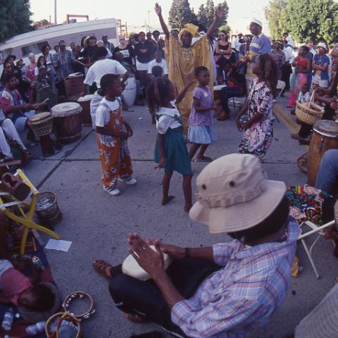 Children and adults dancing in a drum circle near Leimert Park, affectionately called Africatown, 1998. Roland Charles Collection, Box 75.