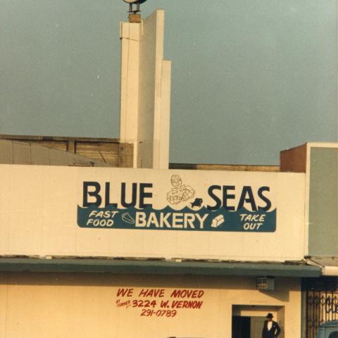 Exterior view of the Blue Seas Bakery, a chain of bakeries throughout the US run by the Nation of Islam. The Nation of Islam, a religious and black nationalist organization, had a strong presence in South LA. The community is well-known for funding its operations by running bakeries that distinctively offer bean pies because their former prophet, Elijah Muhammad, promoted eating navy beans. Circa 1980-1989. Roland Charles Collection, Box 78. 