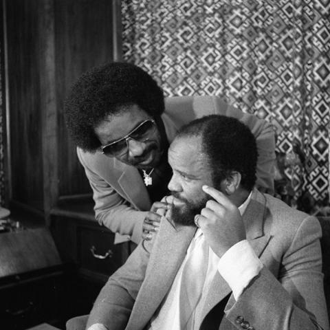 Stevie Wonder leans near to talk with Motown founder Berry Gordy who is siting at his desk in his office. Guy Crowder Collection