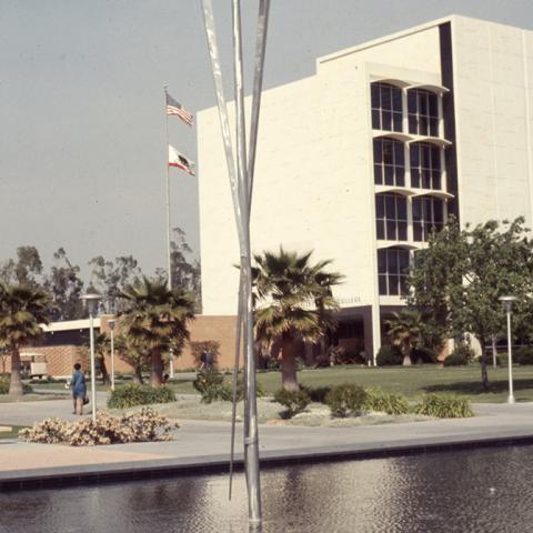 Facing northeast, the reflecting pool with a kinetic sculpture by George Rickey and the Administration building (Bayramian Hall), ca. 1972. 