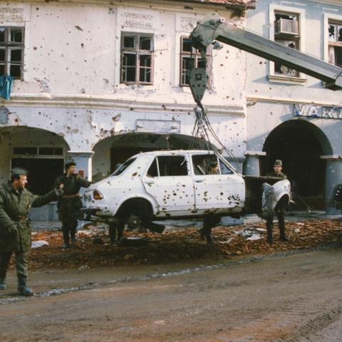 Croatian soldiers tow away a destroyed automobile in the aftermath of conflict. ca. 1991-1994. Box 1, Folder 12.