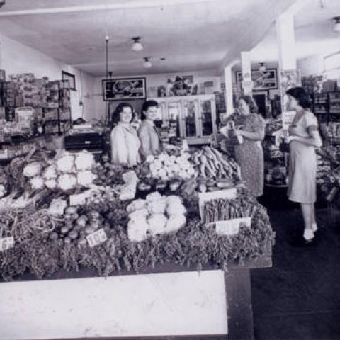 Logreco’s Market, Anne and Mary Logreco behind produce counter helping two women customers.The location was later Warner's Boot Shop. Tujunga, ca. 1940, 	ID: LLHS87