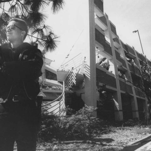 A police officer stands near a damaged parking structure on the corner of Zelzah and Plummer