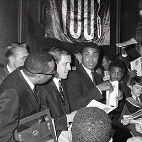 Muhammad Ali surround by people and signing autographs. Harry Adams Collection. ID: 93.01.HA.B2.N35.249