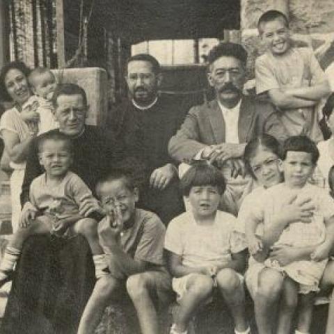 Photograph of family posing with two Catholic priests