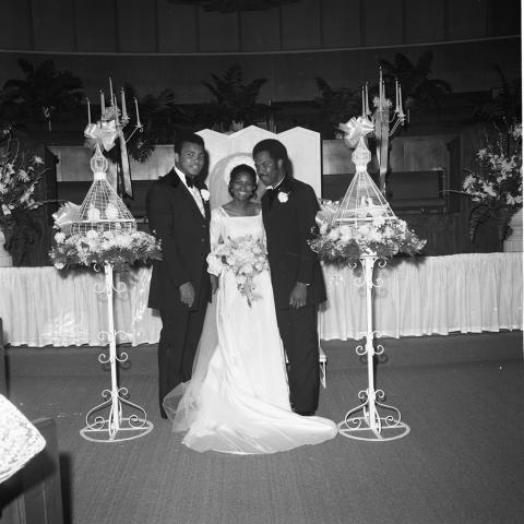 Heavyweight boxing champion and best man Muhammad Ali (left) poses with his long-time friend and personal photographer, Howard Bingham and his bride Carolyn Turner, 1972. Harry Adams Collection. ID: 93.01.HA.N120.B10.08.34.03
