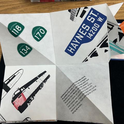 unfolded Turkish Map Folds with freeway signs, a train, a street sign and text about the San Fernando Valley; Visualizing a History of the San Fernando Valley by Carlos Godoy, N7433.4.G63 V57 2019