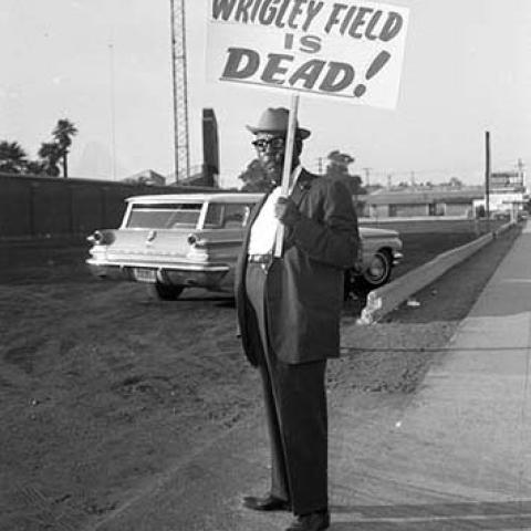 Leon Washington, publisher of the Los Angeles Sentinel, holds a	sign stating “Wrigley field is dead!” while protesting the decision to tear down Wrigley Field. 1964, Harry Adams Collection, 93.01.HA.B6.N45.1127