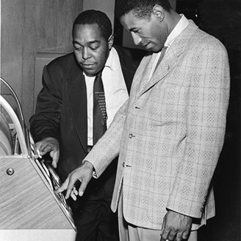 Saxophonist Charlie Parker and drummer Max Roaching looking at a juke box. Los Angeles, 1953.