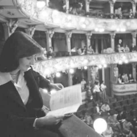 A woman reading a program while sitting in the balcony