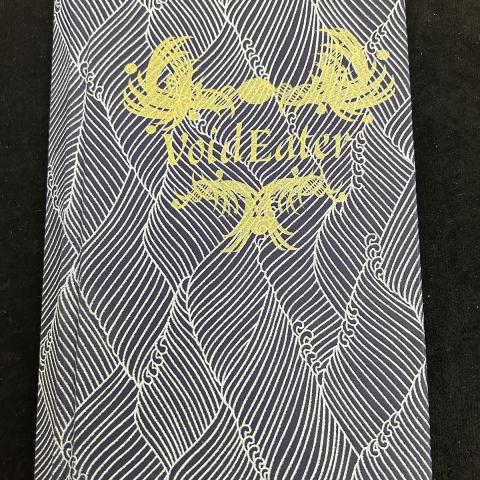 patterned cloth book cover with title in gold; Void Eater by Erick Romero, N7433.4.R66 V65 2019
