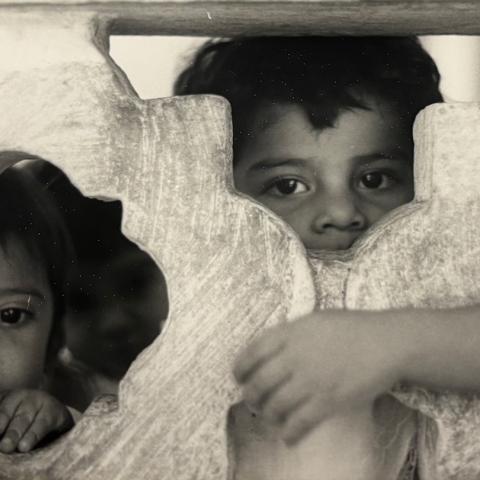 Image from collection selected by Student Assistant, Jenesy: A toddler and a baby peeking through a wall looking at the camera, ca.1982