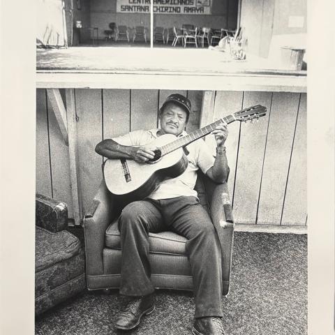 Image from collection selected by Student Assistant, Jenesy: A middle-aged man playing guitar and a sign that says, “Comite De Refugiados Centroamericanos Santana Chirino Amaya," undated.