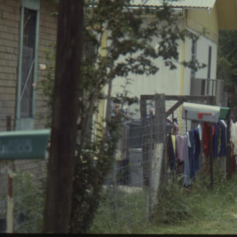 A resident hangs her clothing to dry along the fence in the front yard. TBC.RCH