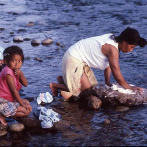 Guatemalan refugees wash clothes in a river, Ixcán, 1983