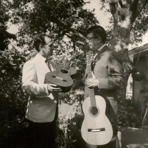 Two men displaying guitars