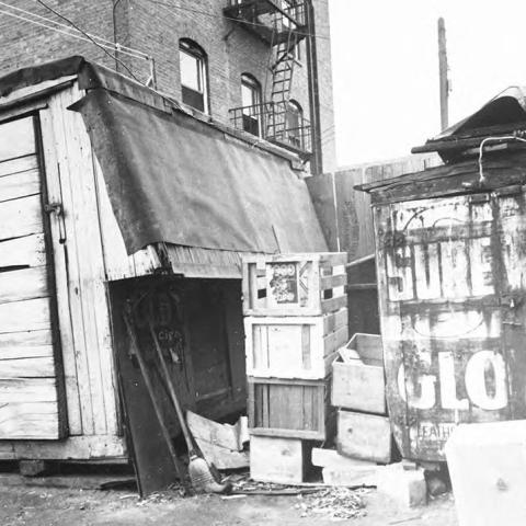 Two makeshift homes sit side by side in an alley. One appears to be an old mobile food truck, and the other a delivery truck. The location is 916 E. 6th St near Skid Row in Downtown Los Angeles.