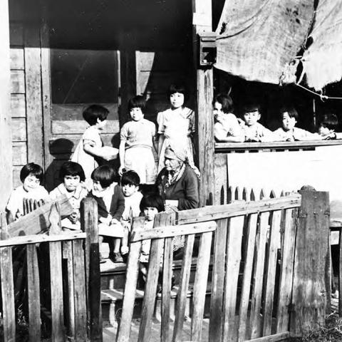 A woman and children on a porch.  This location is now occupied by William Mead Homes public housing project in Chinatown.
