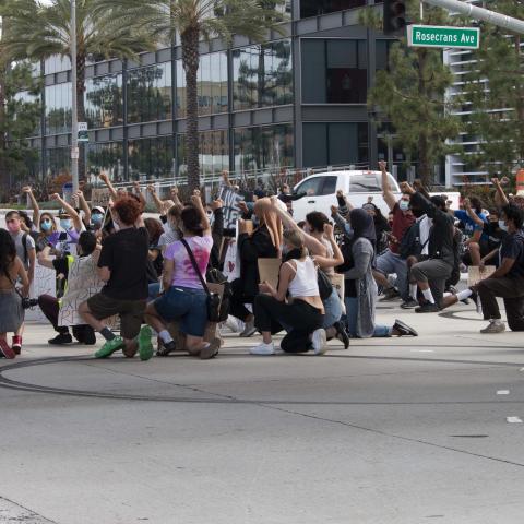 Individuals kneel in the street while holding posters and raising their fists in the air during a protest to Defund the Police at Del Aire Park., Hawthrone, 2020, KRT.D.B1.4.3123