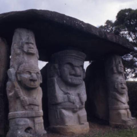 Three giant statues standing under a large stone slab at San Agustín Archaeological Park. Photo taken in 1975. Digital ID: 99.01.RCr.sl.B17.04.19.04