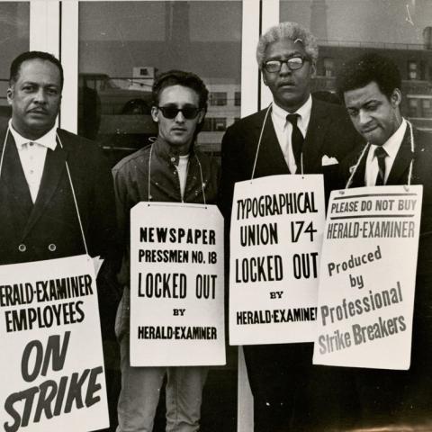 Four picketers standing outside the Herald-Examiner Building