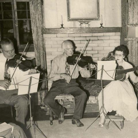 Well-dressed men and young woman playing in ensemble, ca. 1960