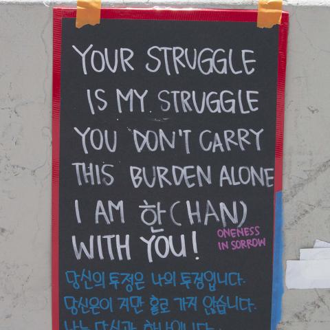 Poster written in English and Korean reads "Your struggle is my struggle. You don't carry this burden alone. I am 'han' (oneness in sorrow) with you” at a "Ktown for Black Lives" event, Koreatown, 2020, KRT.D.B1.11.3492 