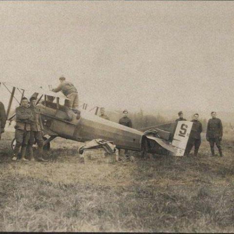 A group of soldiers stand by an airplane, circa 1918
