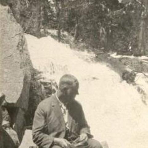 Man sitting by a waterfall, ca. 1922