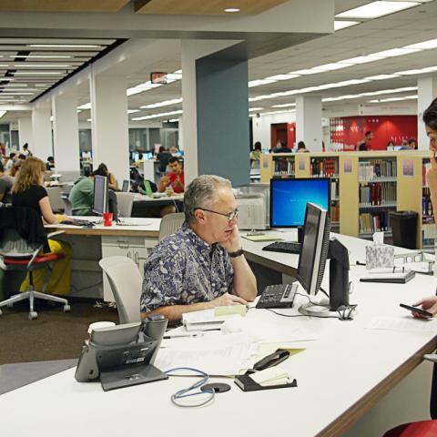 Librarian Michael Barrett helping a student at the new reference desk.
