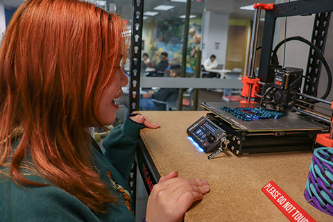 student watches 3d printer in action