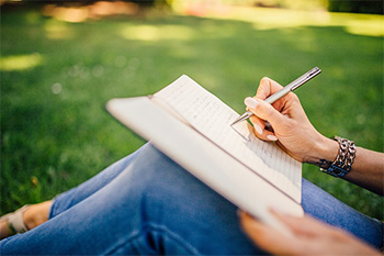 Woman writing in journal outside