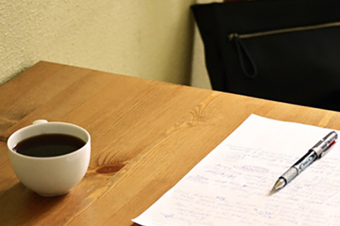 Coffee on a table with paper and a pen
