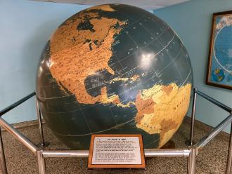 Large globe of earth surrounded by metal rails in corner of a room