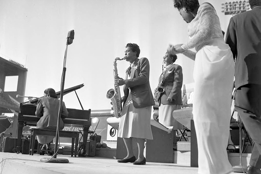 Saxophone player solos surrounded by band members