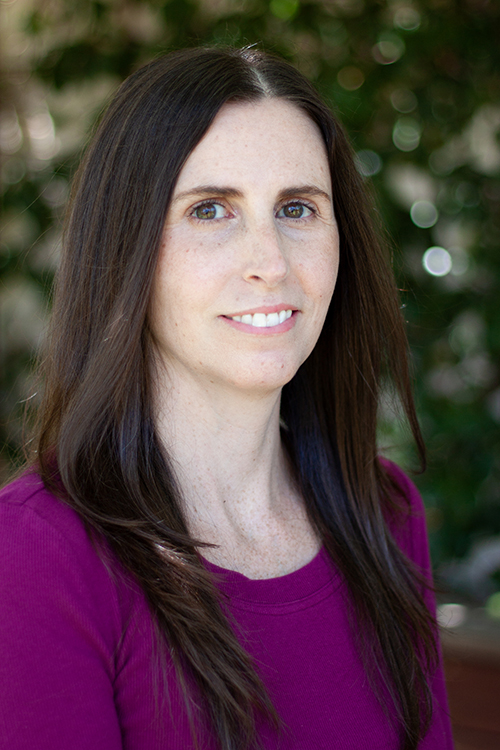 Profile of Alyssa Arentoft wearing a purple sweater with long hair in the outdoors