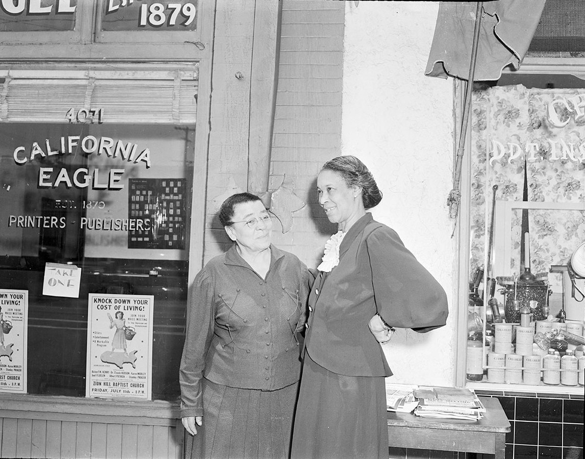 Image of Charlotta Bass and Mrs. Bloodworth standing outside of the California Eagle office