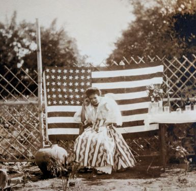 Marie in front of forty-eight star American flag, ca. 1912.
