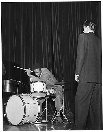 Max Roach playing the drums with Chet Baker looking on, Riverside, 1953.