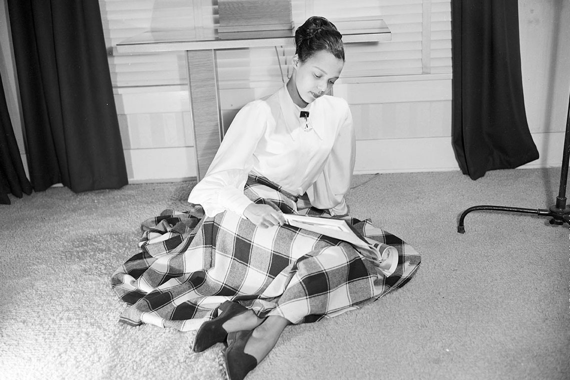 Image of Dorothy Dandridge sitting on the carpet reading