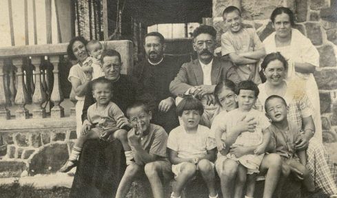 Photograph of family posing with two Catholic priests