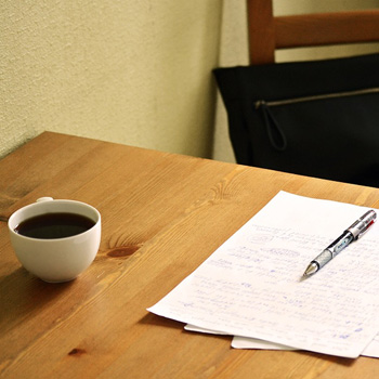 Coffee on a table with paper and a pen