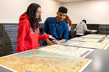students looking at maps in the university library map collection