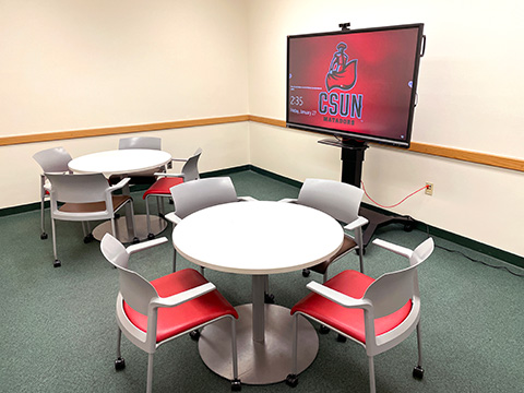 Interactive display study room, featuring two tables with four chairs each